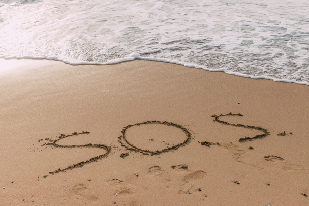 letnia plaża z napisem sos na piasku w pobliżu morza  - Zdjęcie, obraz