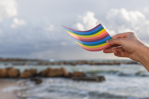 recortado vista de la mujer sosteniendo arco iris lgbt bandera cerca del mar
 - Foto, Imagen