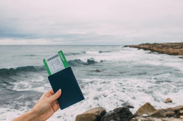 Ausgeschnittene Ansicht einer Passbesitzerin mit Flugticket in Mittelmeernähe  - Foto, Bild