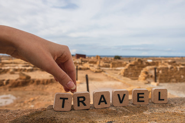 cropped view of woman touching wooden cubes with travel lettering near ruins of ancient House of Theseus   - Photo, Image