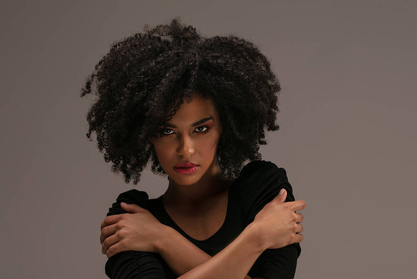 Güzel Afrikalı Amerikalı kadın kameraya bakıyor. Afro saçlı neşeli genç bir kadının portresi. Kıvırcık saçlı güzel kız.. - Fotoğraf, Görsel