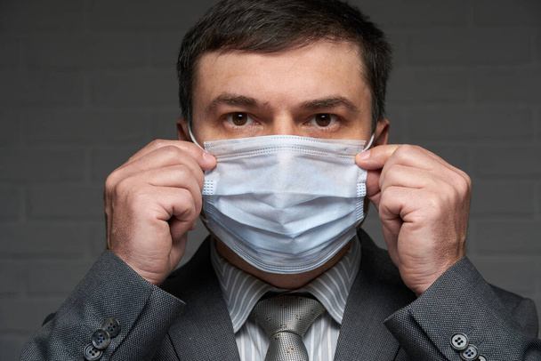 Bir adam antivirüs bireysel korunması için yüzüne maske takar - sağlık ve tıp konsepti, önleme ipuçları - Fotoğraf, Görsel