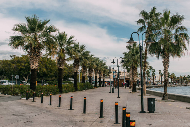 PAPHOS, CYPRUS - MARCH 31, 2020: street lamps near green palm trees and mediterranean sea - Photo, image