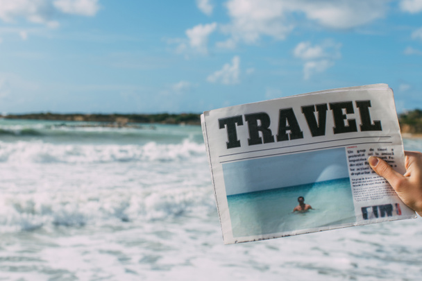 cropped view of woman holding travel newspaper near sea  - Фото, изображение