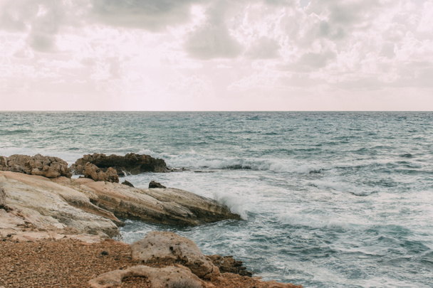 ακτογραμμή με πέτρες κοντά στη Μεσόγειο θάλασσα ενάντια στον ουρανό με σύννεφα  - Φωτογραφία, εικόνα