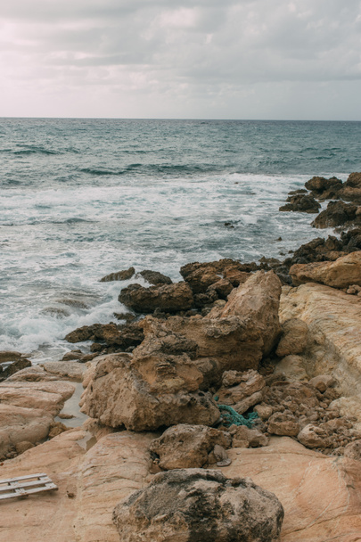 costa tranquila con piedras cerca del mar Mediterráneo contra el cielo con nubes
  - Foto, Imagen