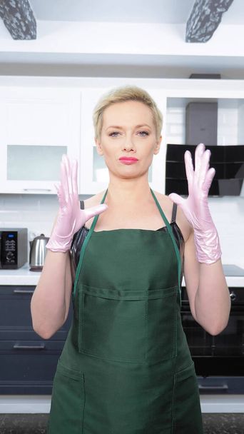vertical shot. woman in leather corset, puts on rubber gloves. cleaning - Foto, Imagen