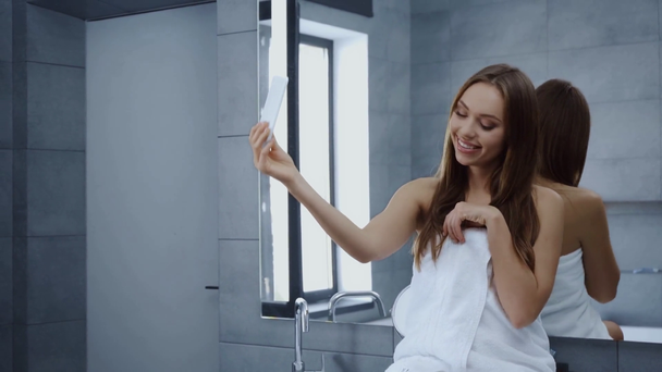 schöne junge Frau winkt Hand und Video-Chat im Badezimmer - Filmmaterial, Video