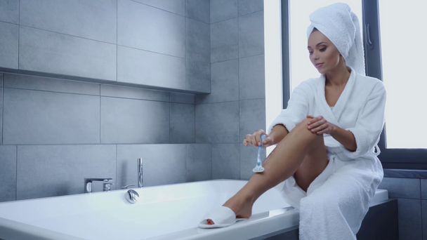 Hermosa mujer joven afeitarse las piernas en el baño
 - Metraje, vídeo