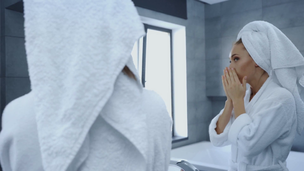 gyönyörű fiatal nő szorító pattanás közben nézi tükör a fürdőszobában - Felvétel, videó