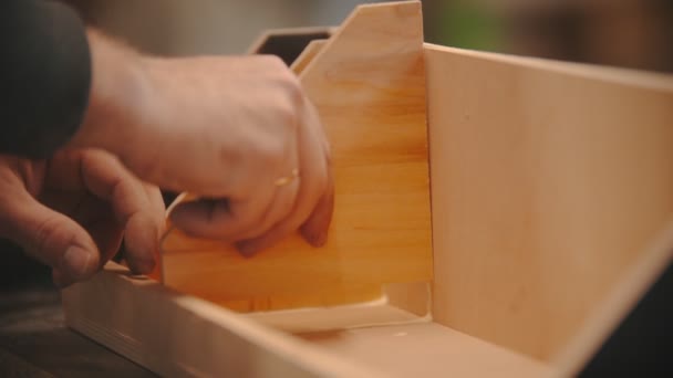 Asztalos munka - férfi munkás keze a fából készült részek ragasztásában - egy fából készült szervező - Felvétel, videó