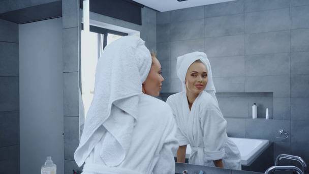 πανέμορφη νεαρή γυναίκα με μπουρνούζι να χορεύει μπροστά στον καθρέφτη στο μπάνιο - Πλάνα, βίντεο