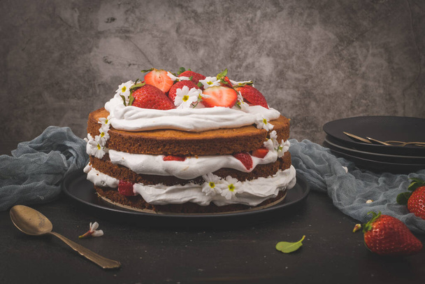 Strawberry cake, strawberry sponge cake with fresh strawberries and sour cream on a dark kitchen countertop. - 写真・画像