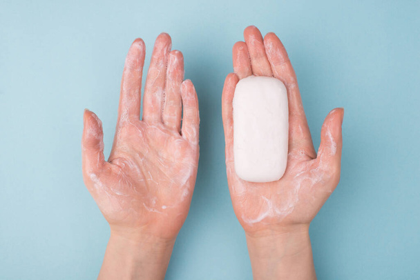 Above top overhead close-up view photo of hands using holding bar of soap and creamy soap isolated over blue color background - Photo, Image