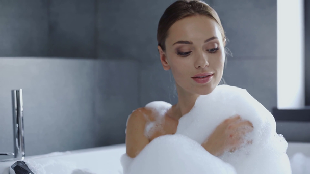 piękna młoda kobieta mycie w wannie z pianką - Materiał filmowy, wideo