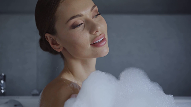 bela jovem mulher lavando no banho de espuma e olhando para a câmera
 - Filmagem, Vídeo