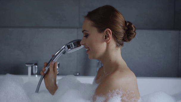 beautiful young woman singing in shower and blowing foam in bubble bath - Video