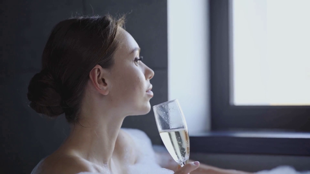 vonzó fiatal nő kortyolgat pezsgőt a pezsgőfürdőben - Felvétel, videó