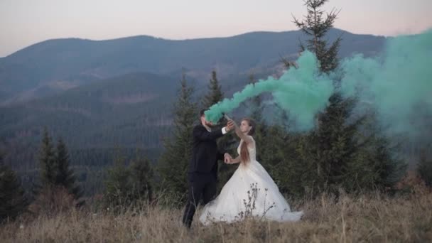 Recién casados. novio caucásico con novia en la pendiente de la montaña con bomba de humo
 - Imágenes, Vídeo