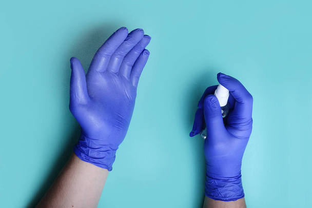Mans χέρια στο μπλε ιατρικά γάντια, κονιορτοποιώντας αντιβακτηριδιακό ψεκασμό.Κάτοψη. - Φωτογραφία, εικόνα