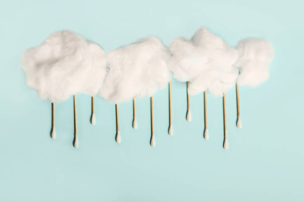 Rain drops from wooden ear sticks.Natural cotton buds for eye cleaning.Fluffy cotton clouds. - Photo, image