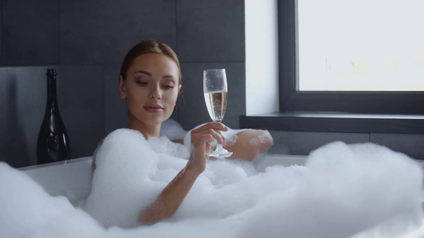 atraente jovem que coloca no banho de bolhas e bebendo champanhe
  - Filmagem, Vídeo