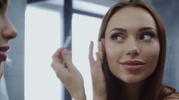 schöne junge Frau zupft Augenbrauen mit Pinzette im Badezimmer - Filmmaterial, Video