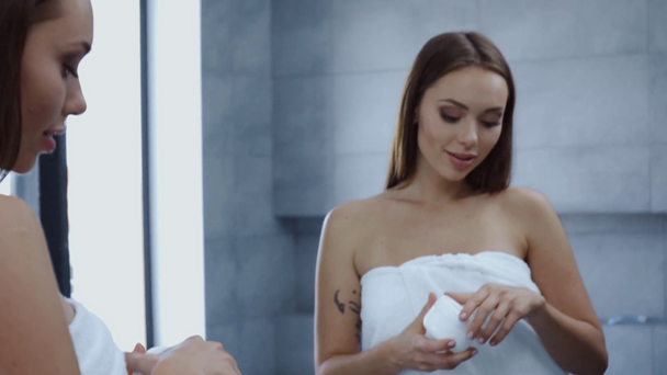 atractiva mujer joven apertura contenedor de crema cosmética en el baño
 - Imágenes, Vídeo