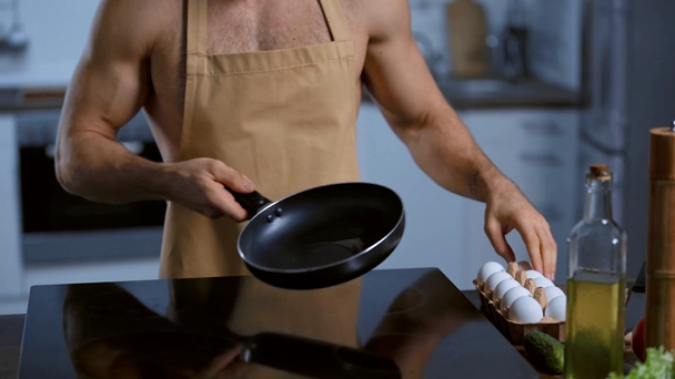 καλλιεργημένη άποψη του γυμνόστηθη άνθρωπος στην ποδιά τηγάνισμα αυγό κοτόπουλου  - Πλάνα, βίντεο