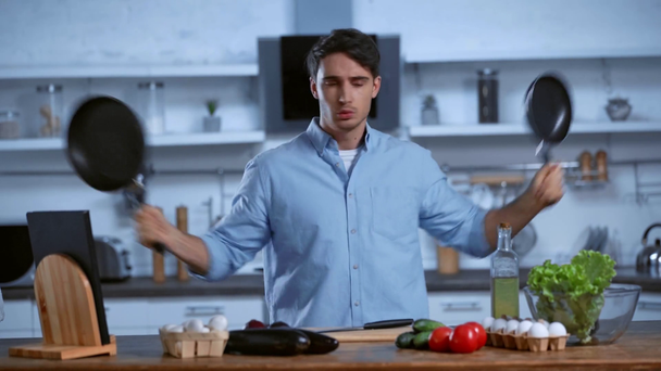 vzrušený muž tančí se smaženými pery u stolu s čerstvými ingrediencemi - Záběry, video