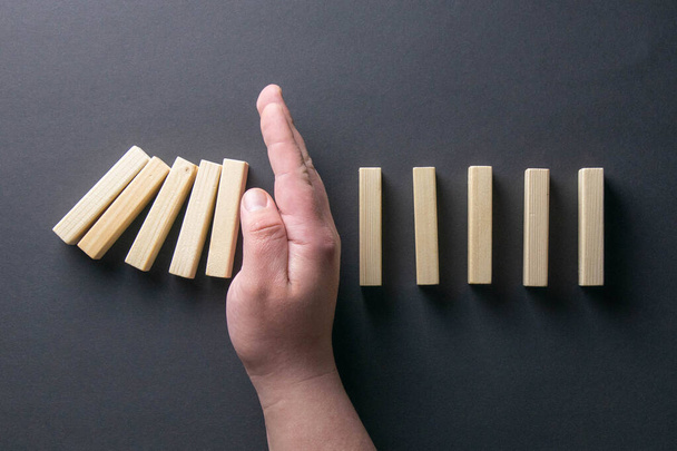 Top view man hand stoppen met vallen dominos in een business crisis management conceptueel beeld. - Foto, afbeelding