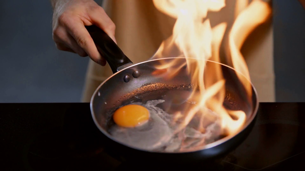 καλλιεργημένη άποψη του ανθρώπου τηγάνισμα αυγό με τη μέθοδο φλαμπέ  - Πλάνα, βίντεο