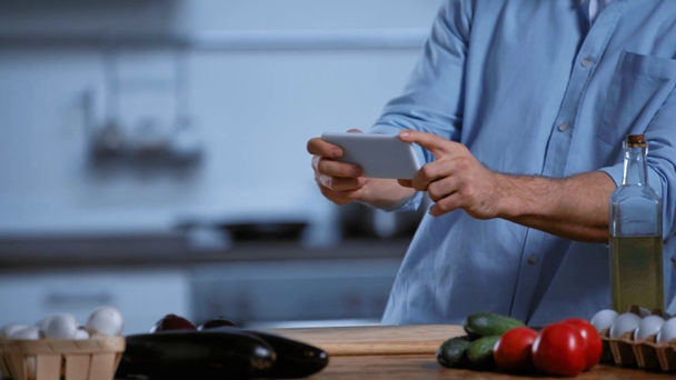 abgeschnittene Ansicht eines Mannes, der frische Zutaten mit dem Smartphone fotografiert - Filmmaterial, Video