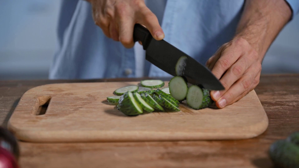 bijgesneden beeld van de mens die verse komkommer snijdt op snijplank  - Video