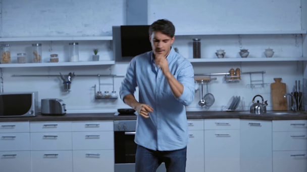 gelukkig man in blauw shirt dansen in moderne ruime keuken - Video