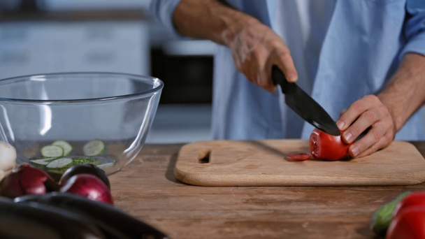 обрізаний вид людини, що ріже помідор біля скляної миски, баклажанів і цибулі
 - Кадри, відео