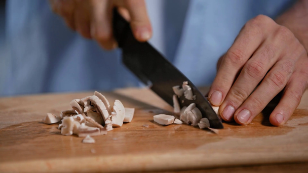 cropped view of man cutting champignons on chopping board in kitchen - Footage, Video