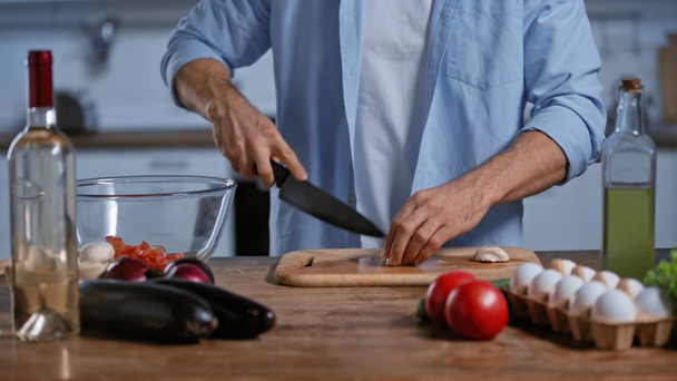 新鮮な野菜や卵やワインの近くでキノコを切る男の姿が切り取られ - 映像、動画