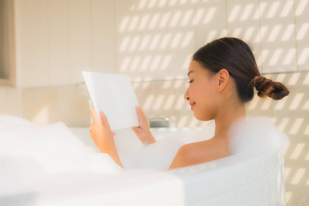Портрет молодой азиатской женщины читать книгу в ванной для спа-концепция
 - Фото, изображение