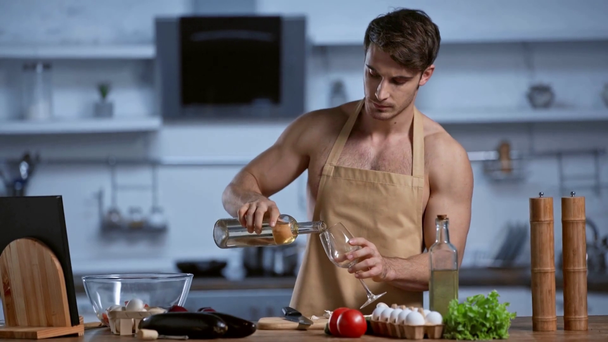 uomo senza camicia in grembiule che cucina in cucina e beve vino bianco
 - Filmati, video