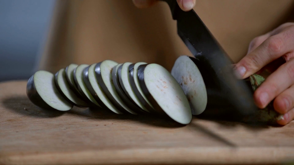 cropped view of man cutting fresh eggplant on wooden chopping board - Footage, Video