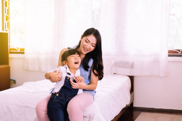 asiatico singolo mamma solletico e portando per allegro figlia in camera da letto felice e divertente
 - Foto, immagini