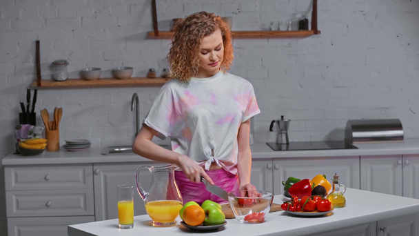 Привлекательная девушка режет свежий салат на кухне
  - Кадры, видео
