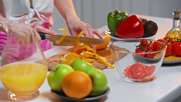 Gesneden weergave van vrouw snijden paprika voor verse salade op tafel - Video