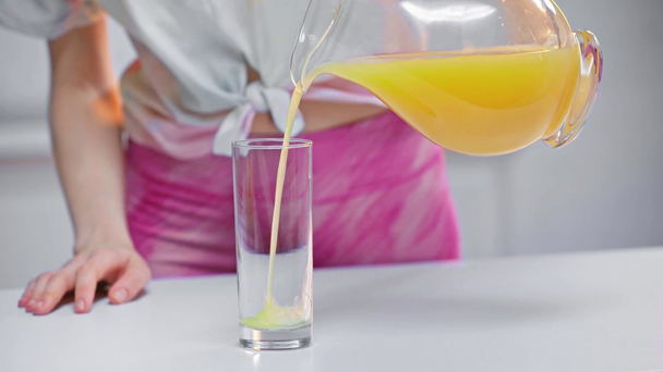 oříznutý pohled na ženu nalévající pomerančovou šťávu ve skle - Záběry, video