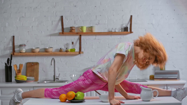 Widok boczny kobiety tańczącej na stole w pobliżu owoców - Materiał filmowy, wideo