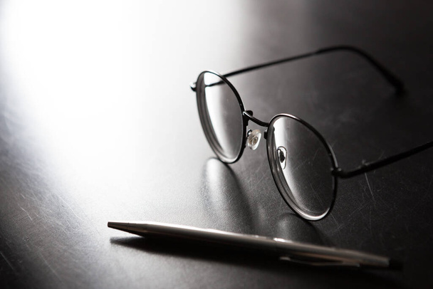 Enfoque selectivo de lápiz, gafas, sobre fondo negro y espacio de copia con luz y sombra
 - Foto, imagen