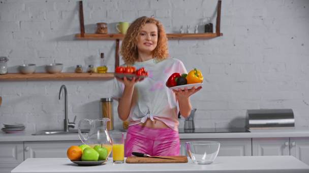 Mujer sonriente bailando con verduras frescas en la cocina
  - Metraje, vídeo