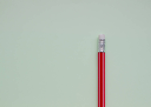 Egy piros ceruza világoszöld háttérrel. - Fotó, kép