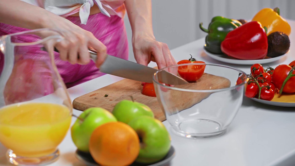 Widok kobiety krojącej pomidory do sałatki w kuchni  - Materiał filmowy, wideo